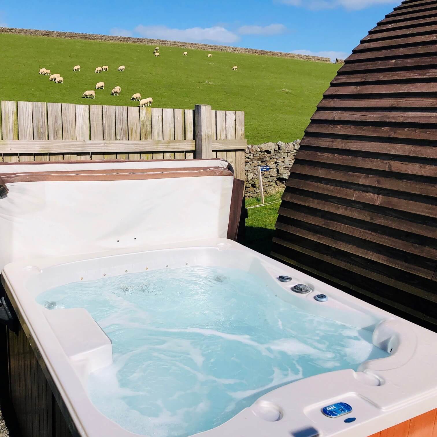 Herding Hill Farms Hot tub with a view of many sheep behind it 